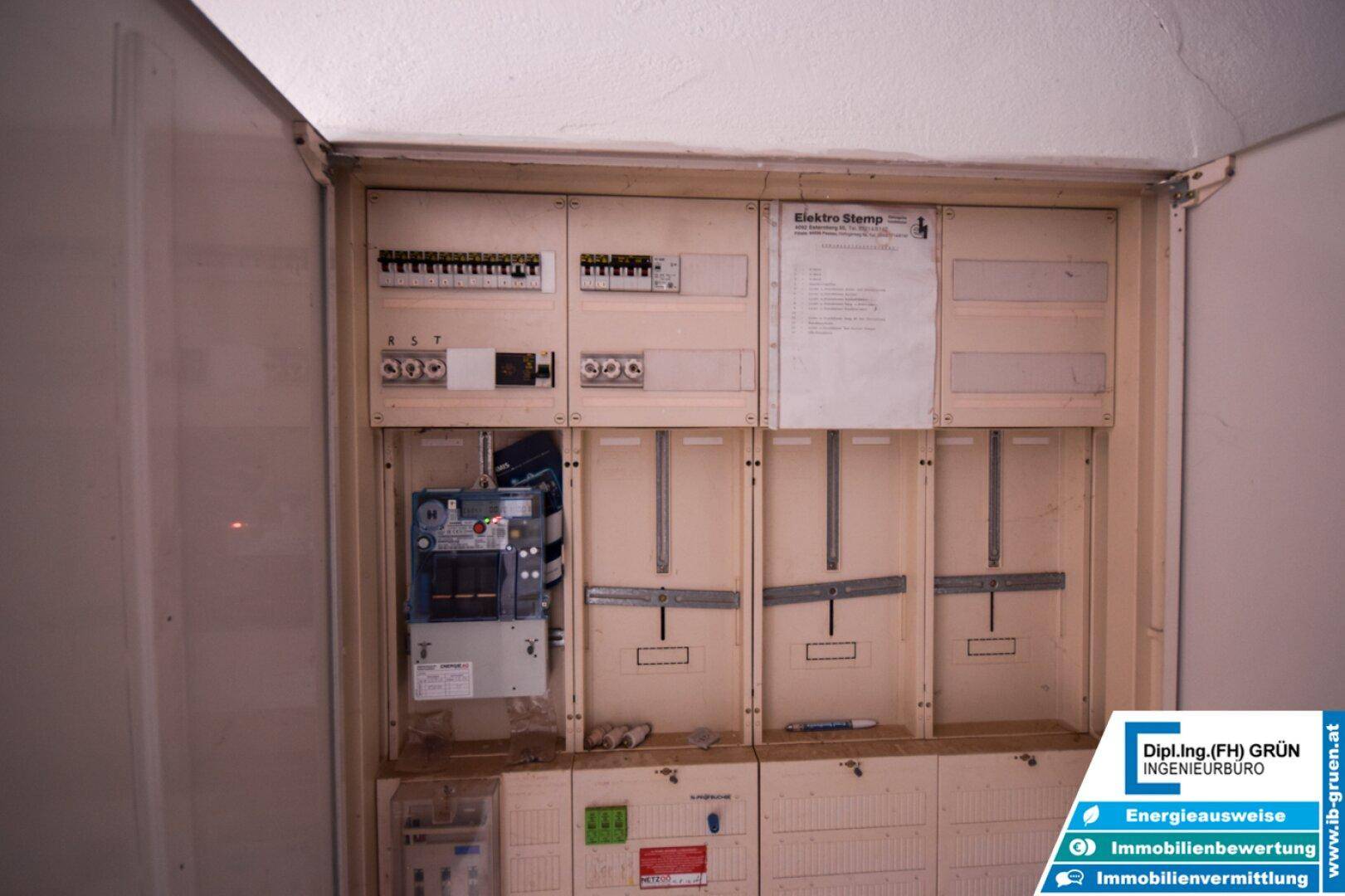 Elektrischer Sicherungskasten mit Zählern und Verkabelung in einem Versorgungsraum.