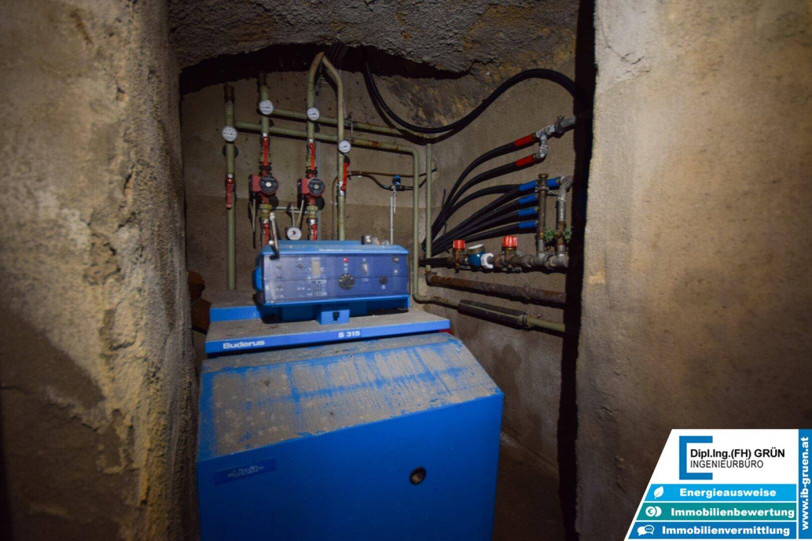 Heizungsanlage mit blauer Kessel- und Pumpeneinheit in einem Technikraum.