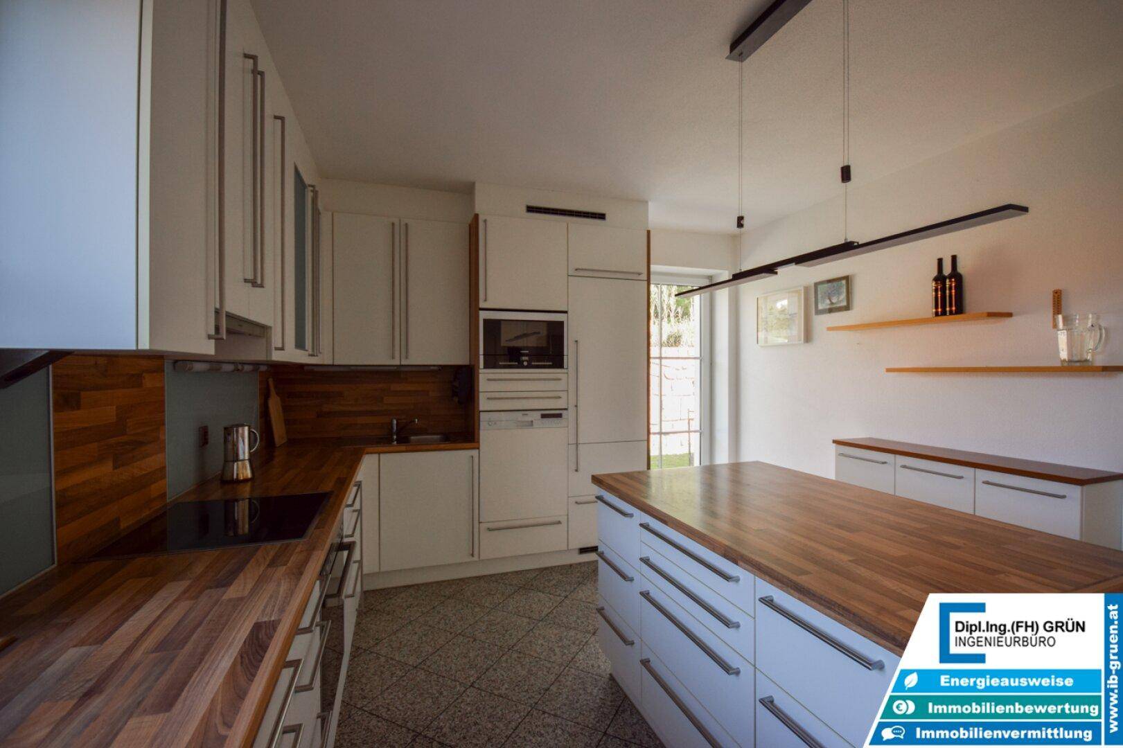 Geräumige Küche mit Holz-Arbeitsplatten, weißen Schränken und modernen Geräten.