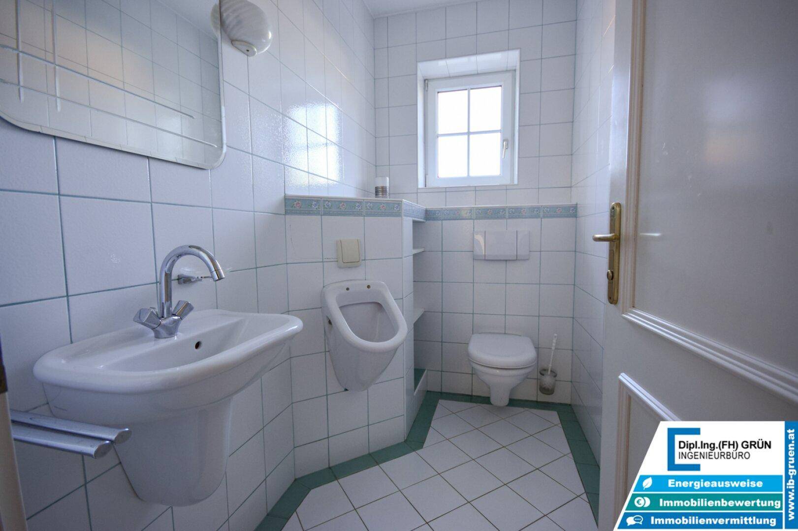 Kleines Gäste-WC mit Fenster, Urinal und weiß-grünen Fliesen.