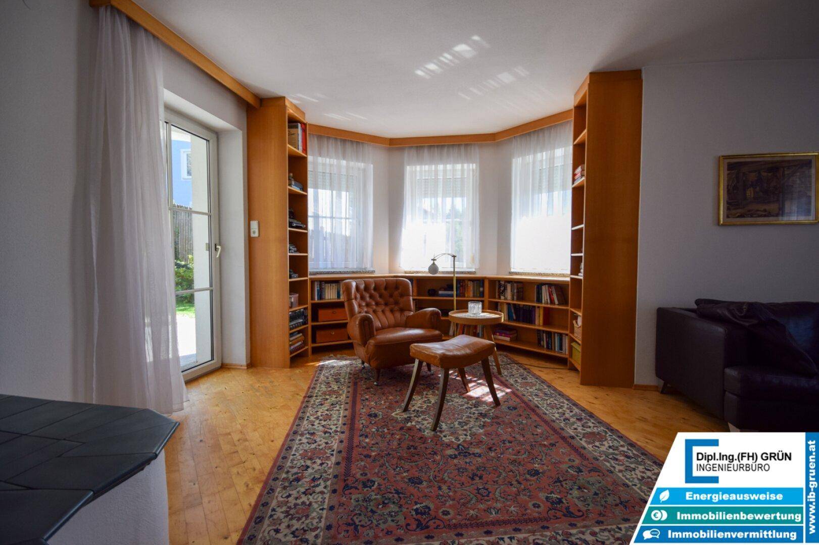 Heller Wohnbereich mit Leseecke, Einbauregalen und Zugang zum Garten.