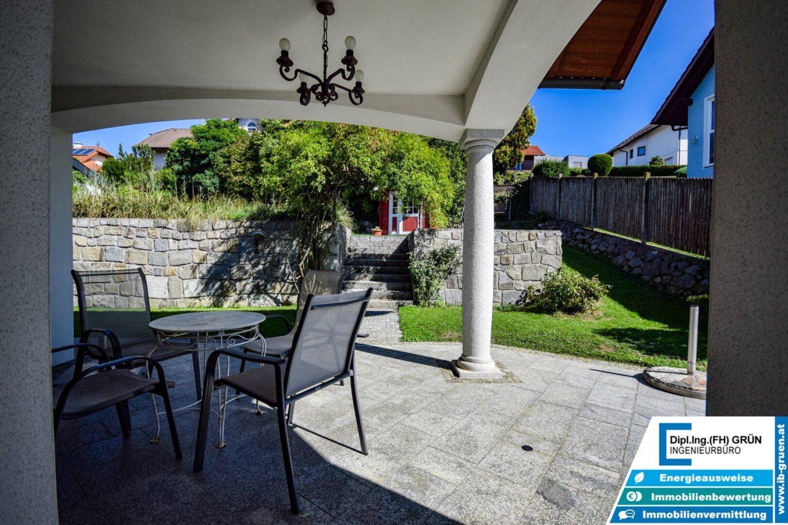 Überdachte Terrasse mit Sitzgelegenheiten und Blick auf den Garten.
