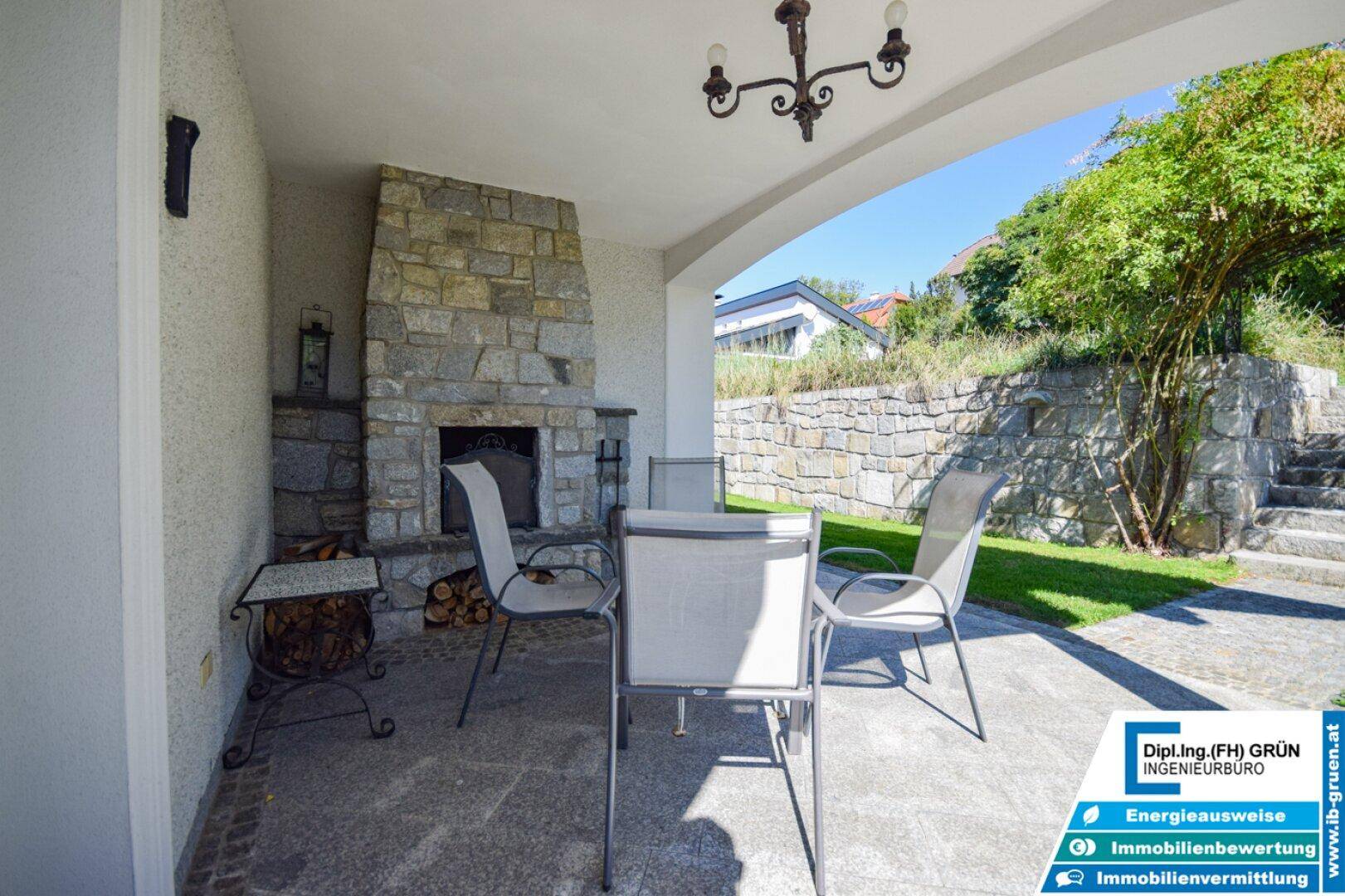 Gemütliche Terrasse mit Außenkamin und Sitzgelegenheiten im Grünen.