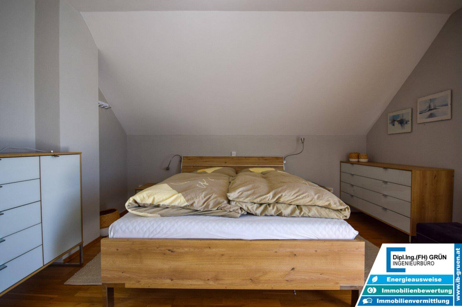 Gemütliches Schlafzimmer im Dachgeschoss mit Holzbett und Kommoden.