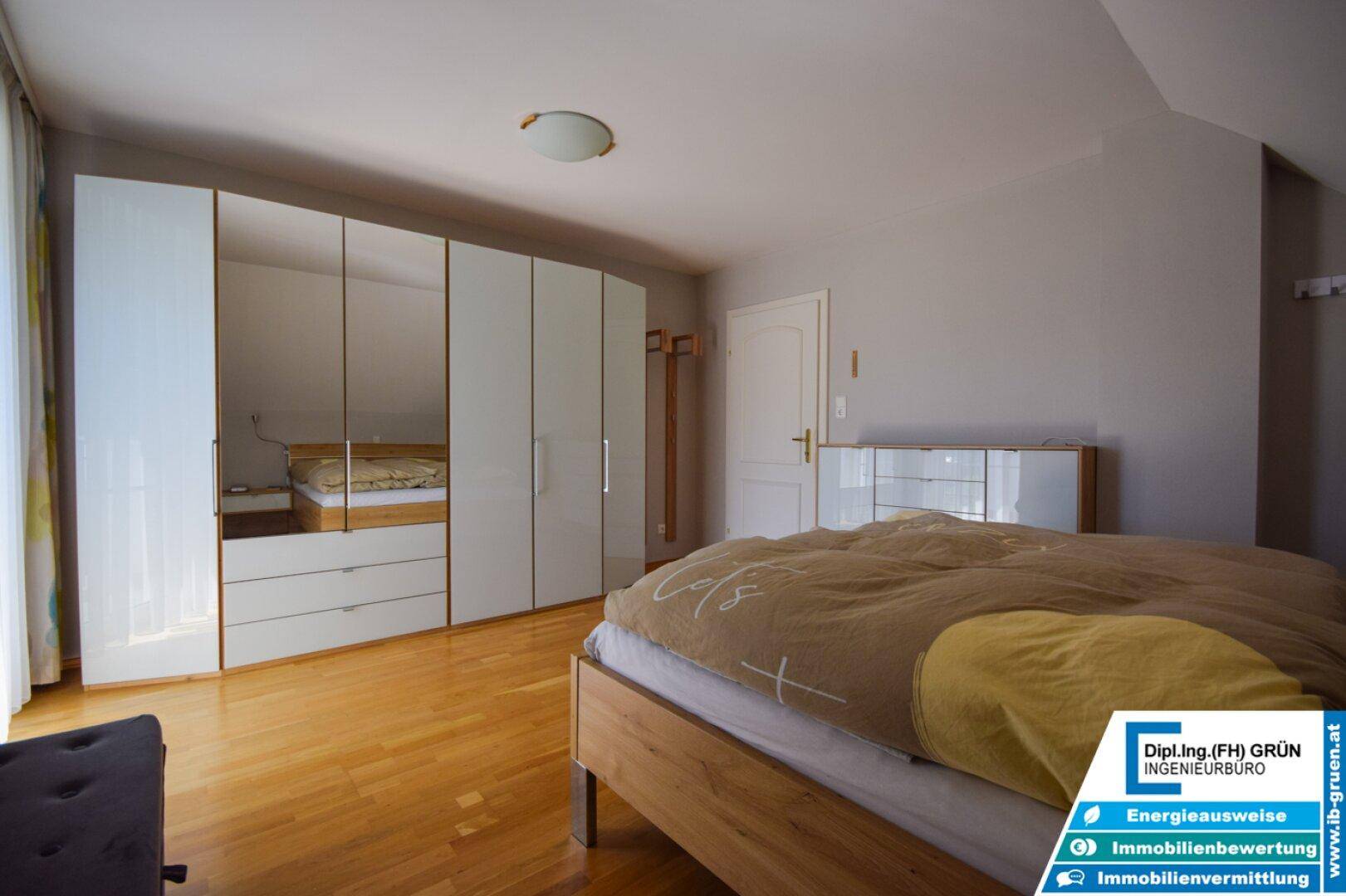 Schlafzimmer im Dachgeschoss mit Holzboden und großem Einbauschrank.
