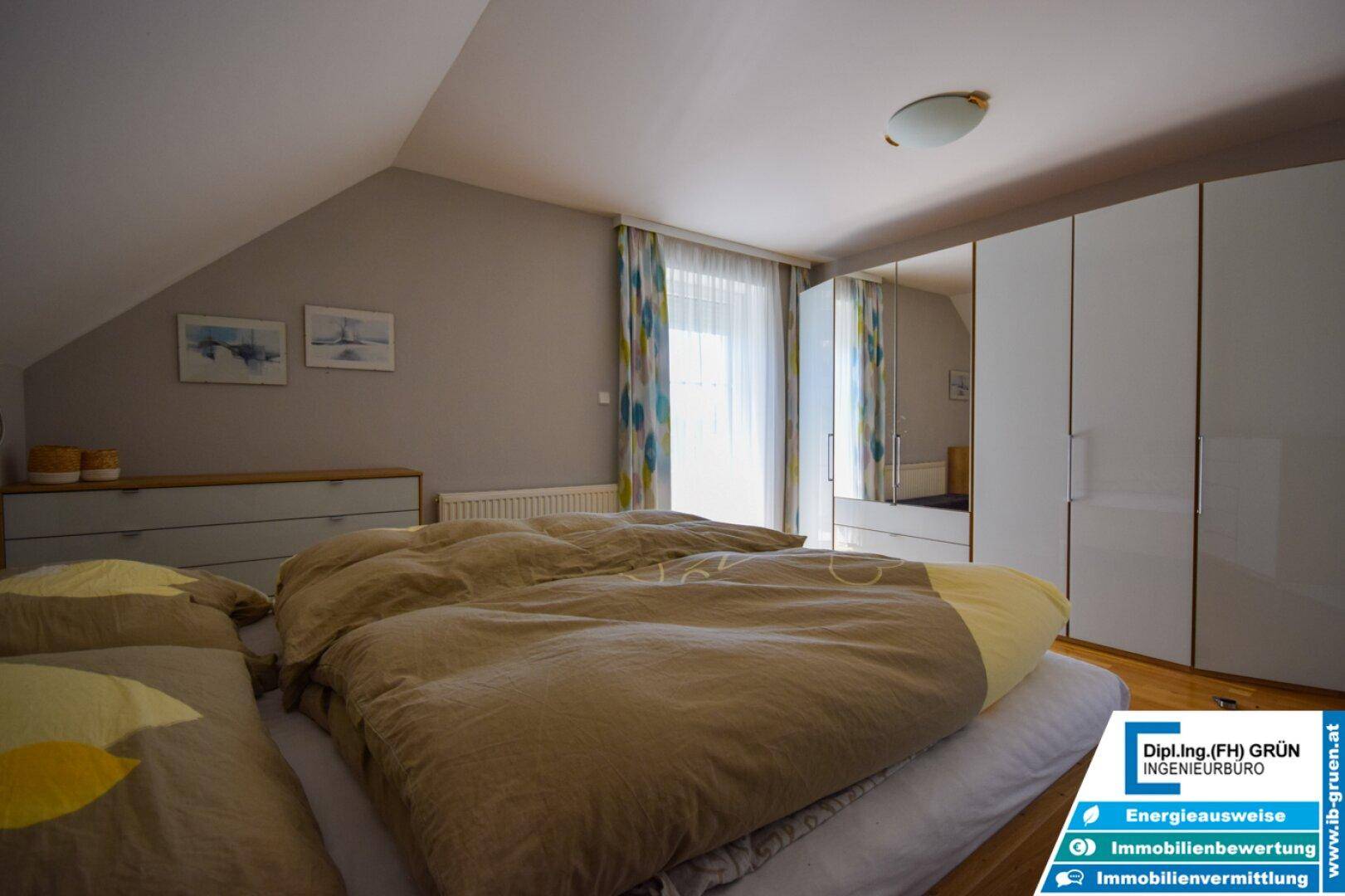 Helles Schlafzimmer im Dachgeschoss mit Holzboden und Fenster.