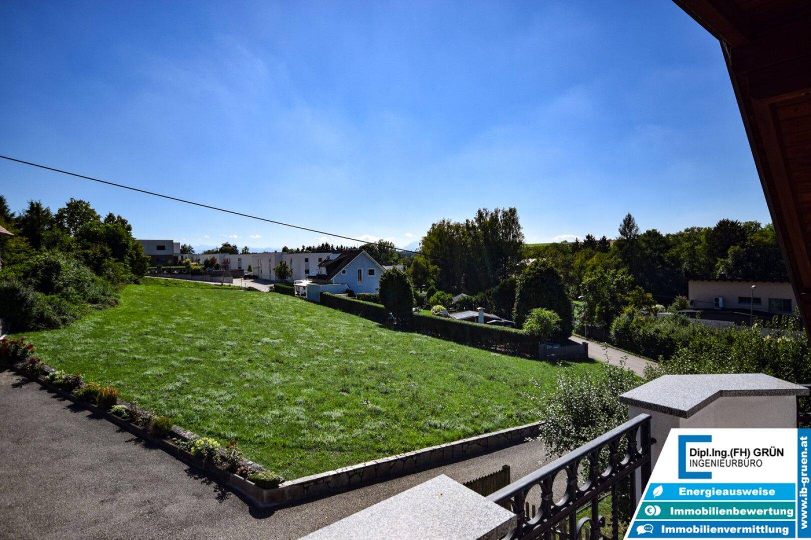 Weitläufiger Blick über grüne Wiesen und die umliegende Landschaft von einem Balkon.