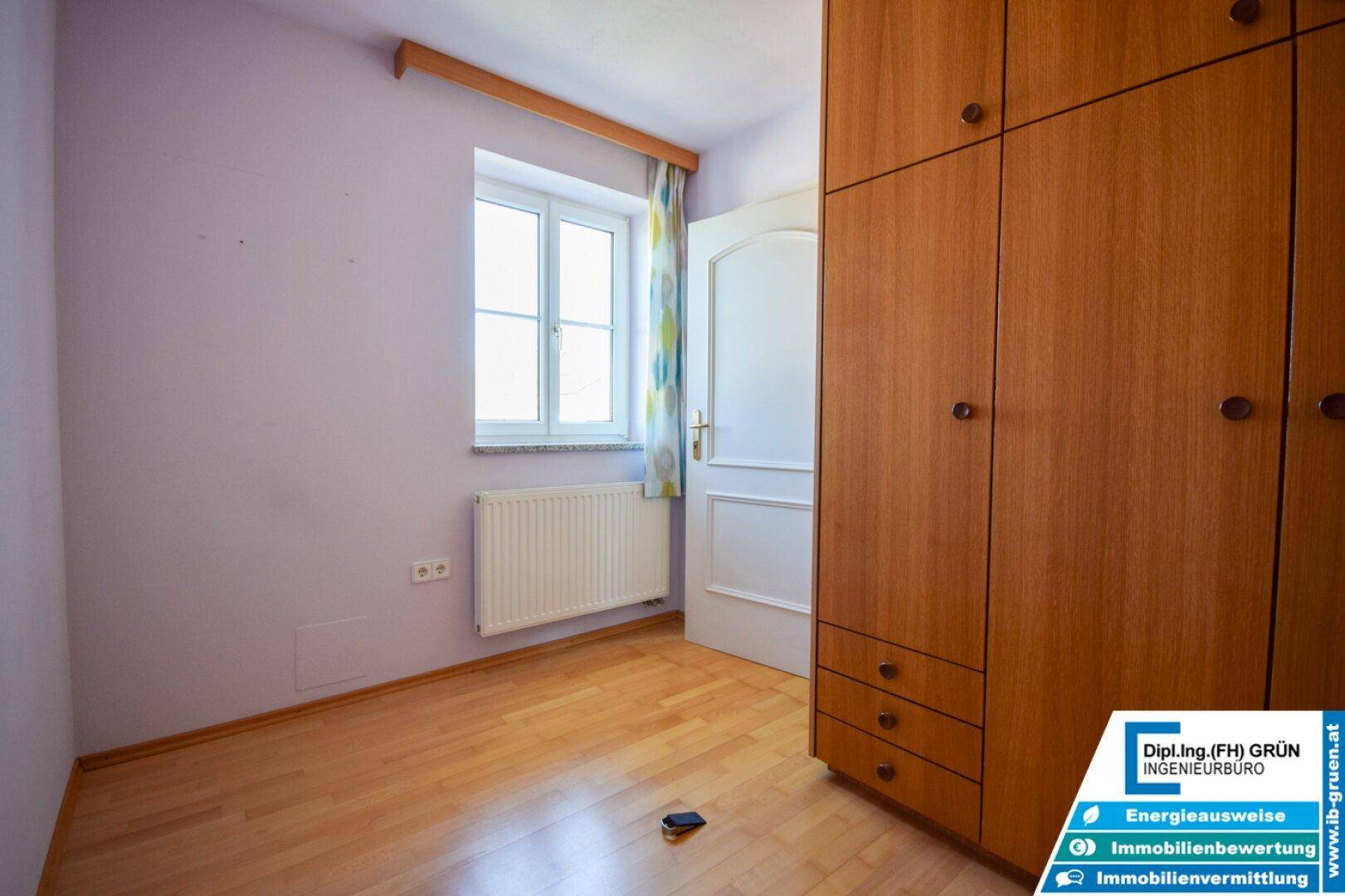 Kleines Zimmer mit Holzboden, Fenster und Heizkörper, ideal als Kinder- oder Gästezimmer.
