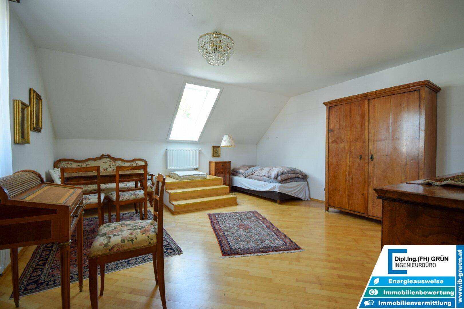Dachgeschosszimmer mit Holzboden, Dachfenster und antiken Holzmöbeln, hell und einladend.