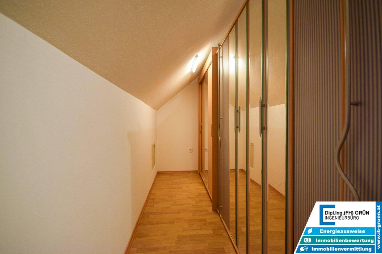 Langer Flur mit Spiegelschränken und Holzboden im Dachgeschoss, hell und funktional.