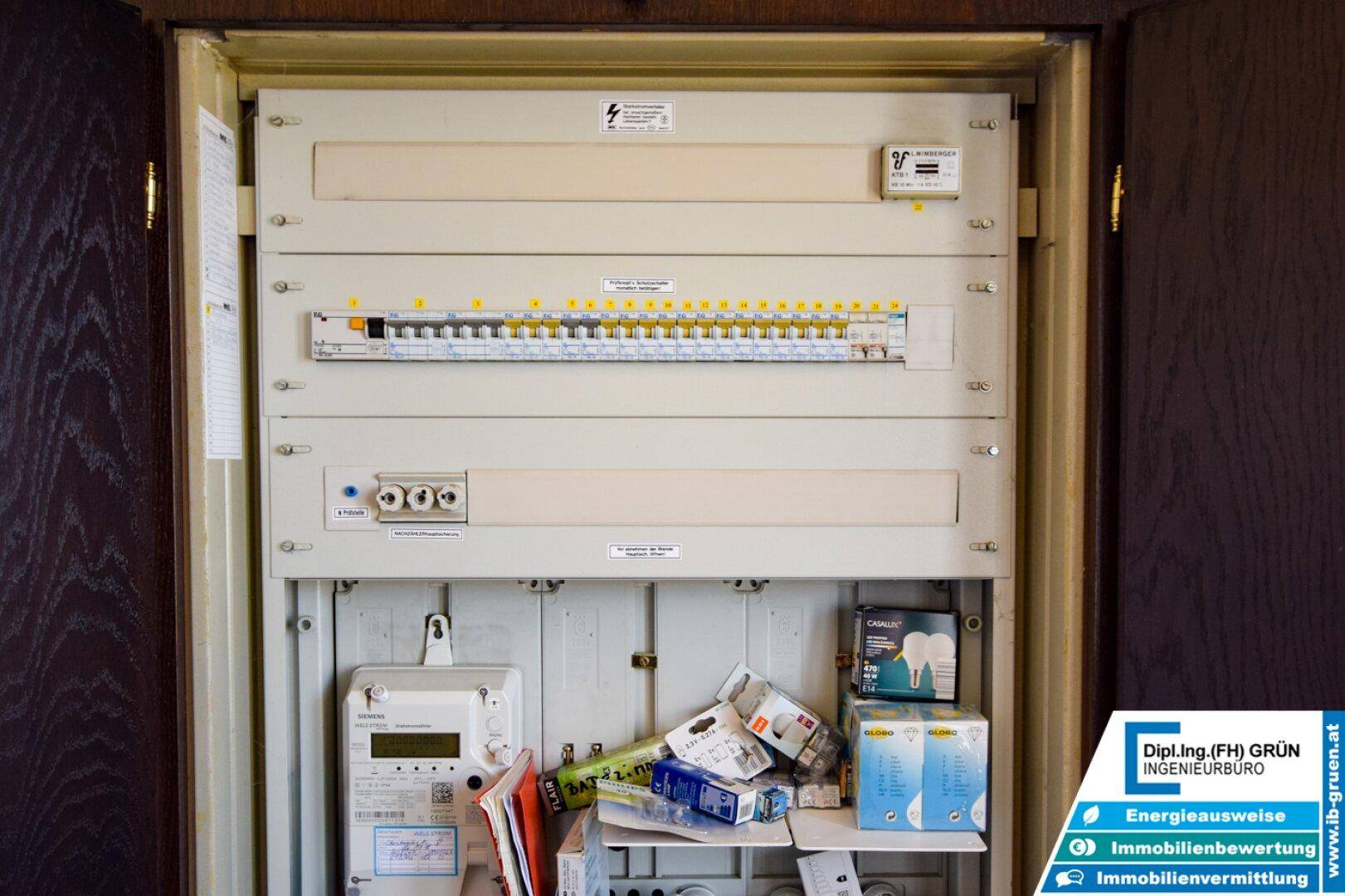 Elektrischer Verteilerkasten und Zähler in einem Technikraum, ordentlich installiert.