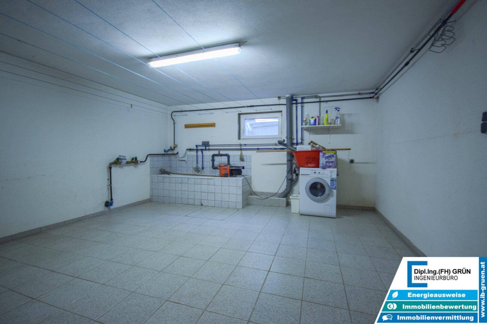 Waschküche im Keller mit Waschmaschine, Spülbecken und Fliesenboden, praktisch eingerichtet.