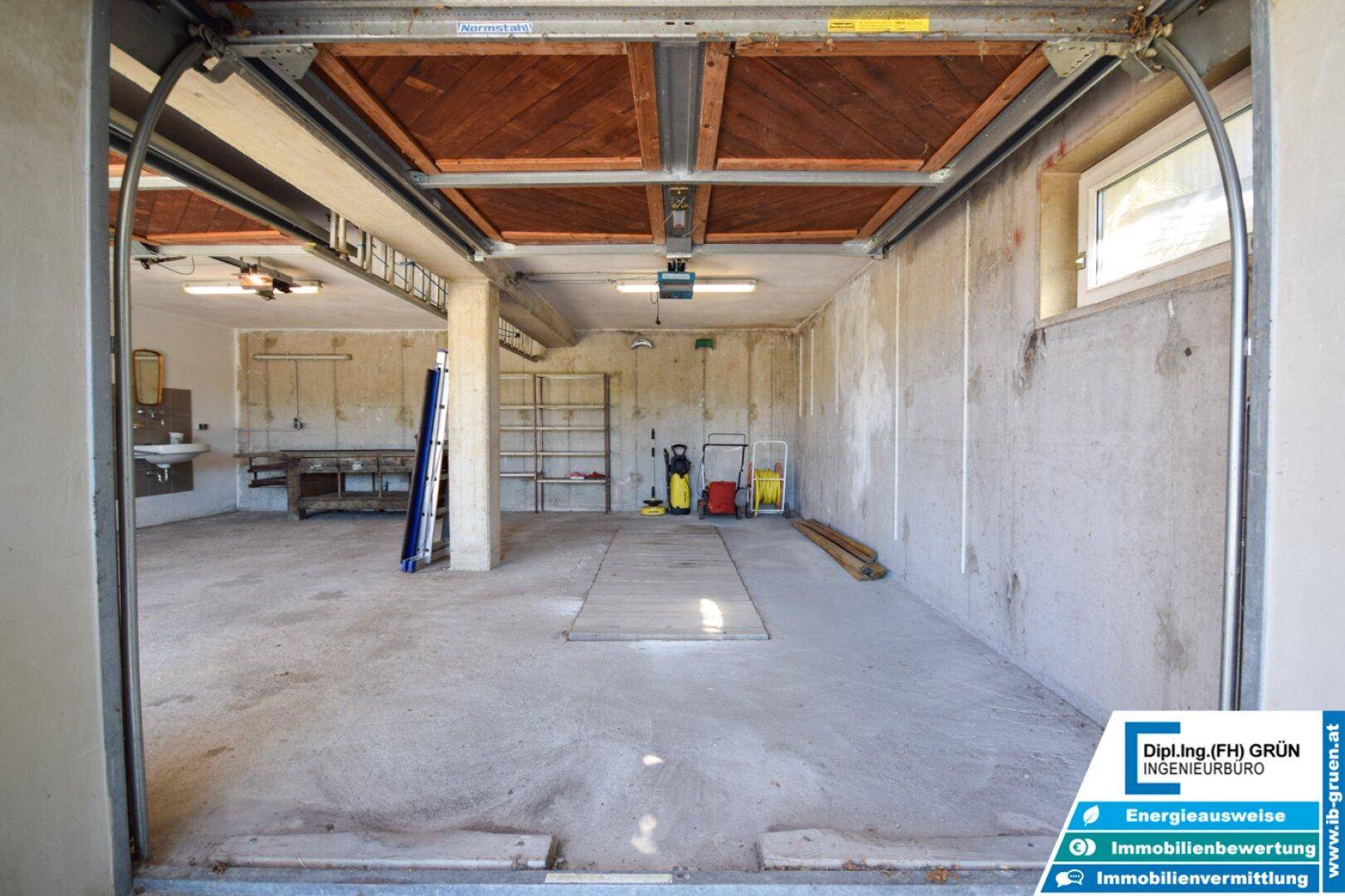Geräumige Garage mit Betonboden, Werkbank und Stauraum für Geräte.