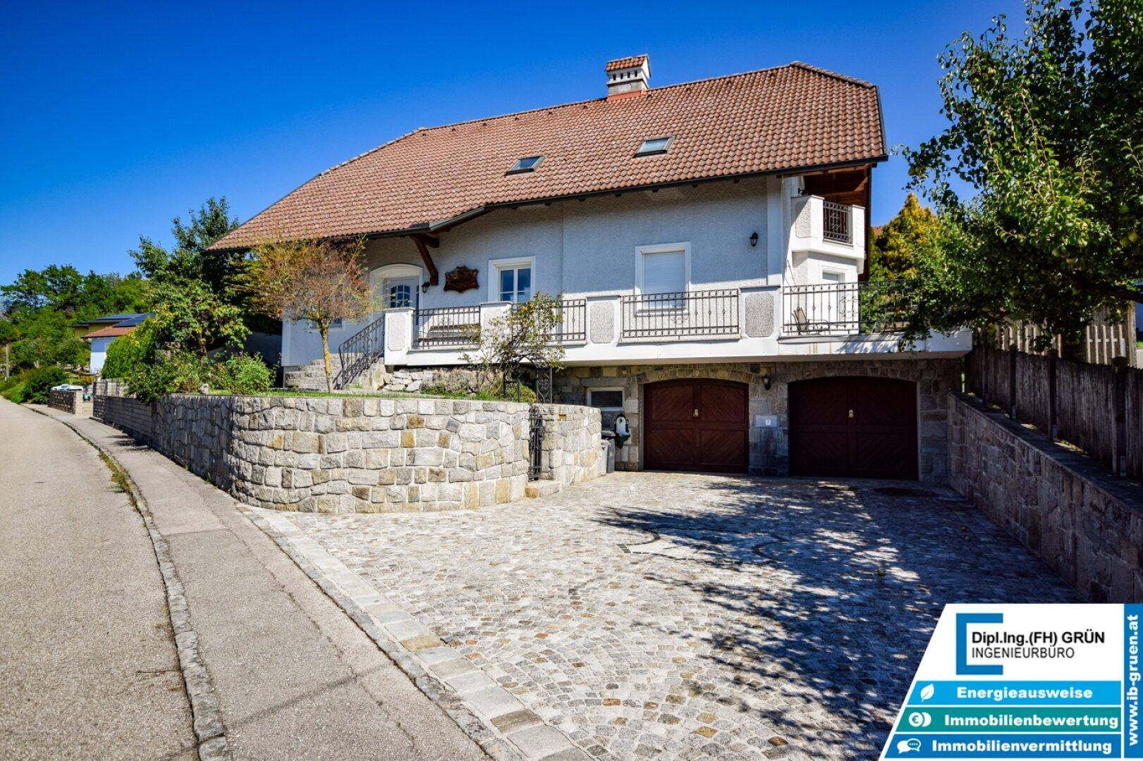 Charmantes Haus mit gepflasterter Auffahrt, Steinfassade und Satteldach.