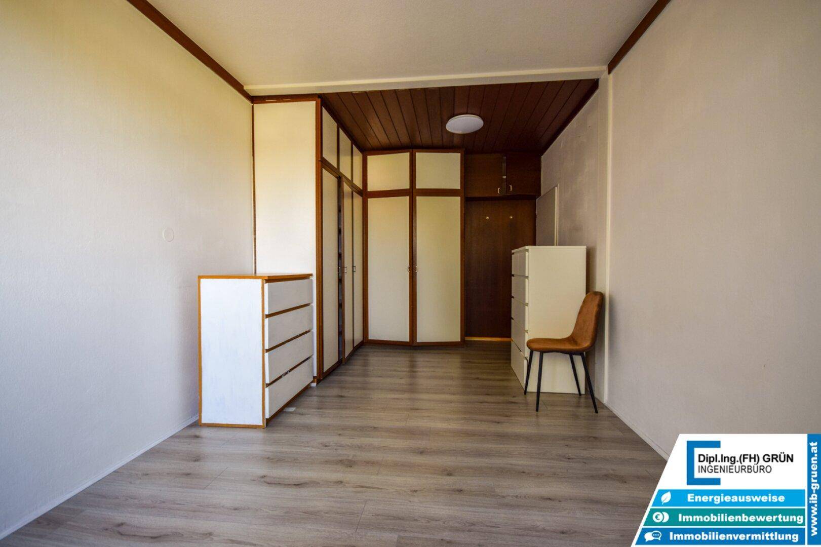 Leeres Schlafzimmer mit Laminatboden, Einbauschränken und Holzdecke.