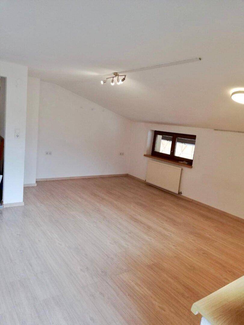Geräumiger, heller Raum mit Laminatboden und schräger Decke, ideal als Schlafzimmer.