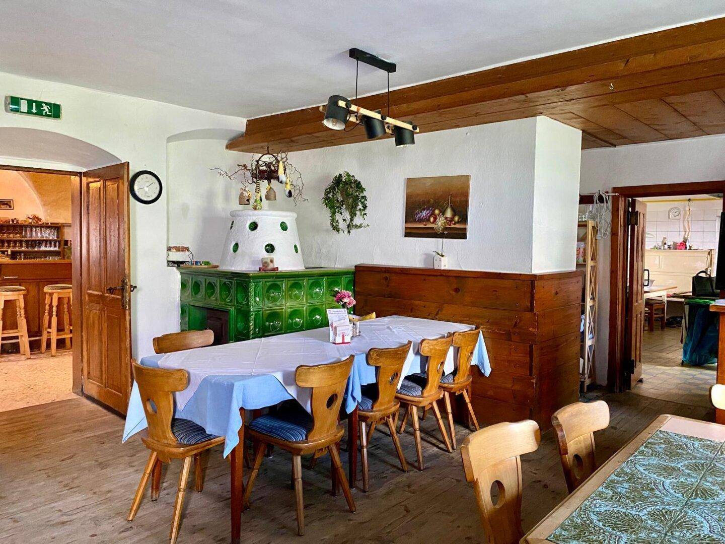 Gemütlicher Essbereich mit traditionellem Kachelofen, Holzbalken und rustikalen Holzmöbeln.