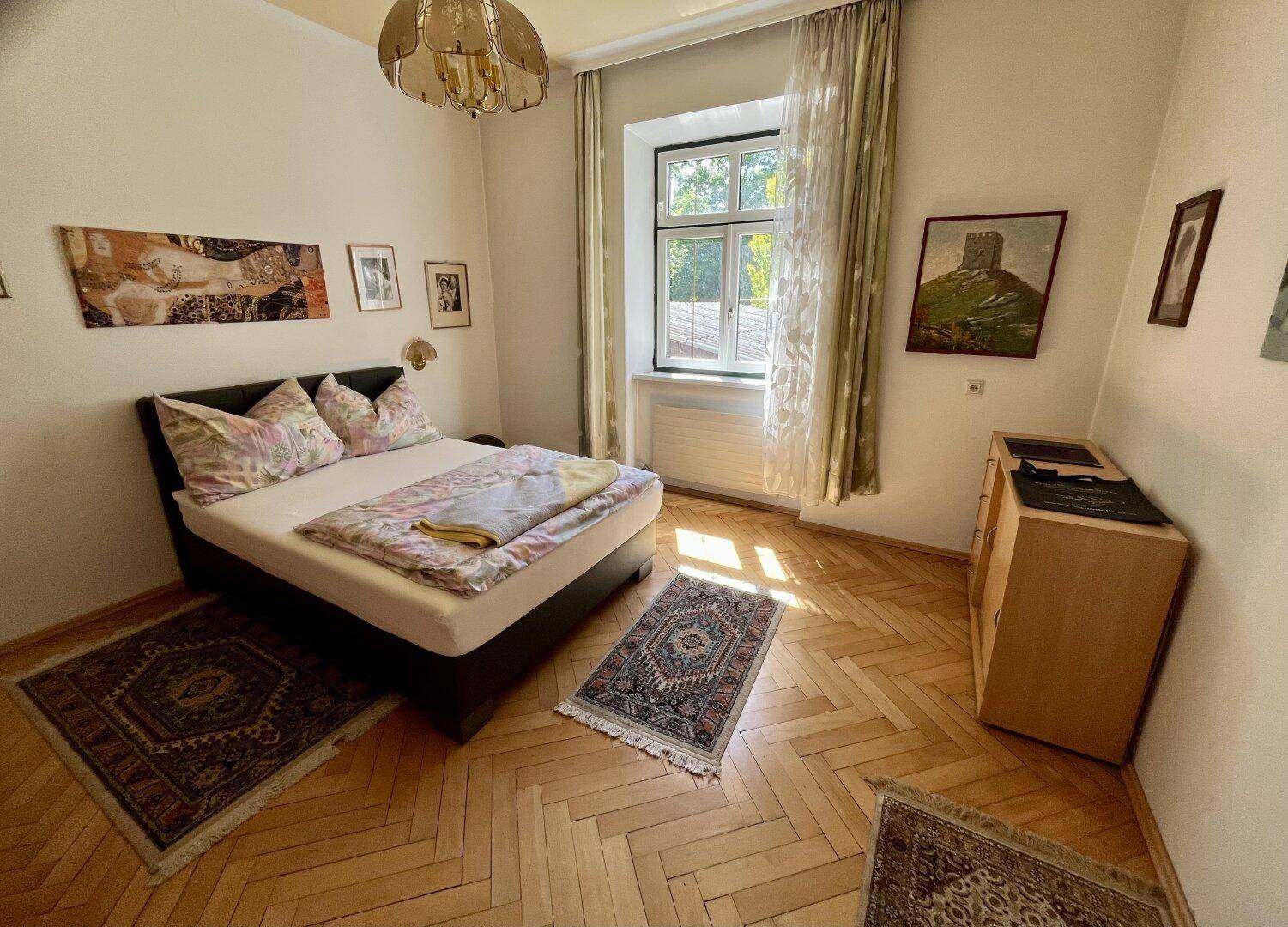 Gemütliches Schlafzimmer mit Fischgrätparkett, Doppelbett und traditioneller Einrichtung.