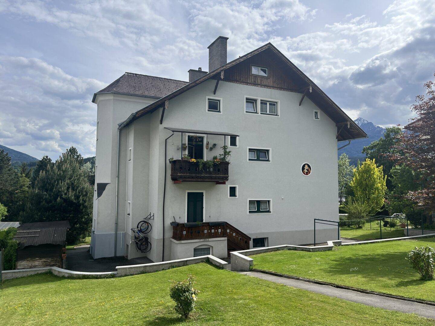 Seitenansicht des Gebäudes mit einem kleinen Balkon und Blick auf die Berge.