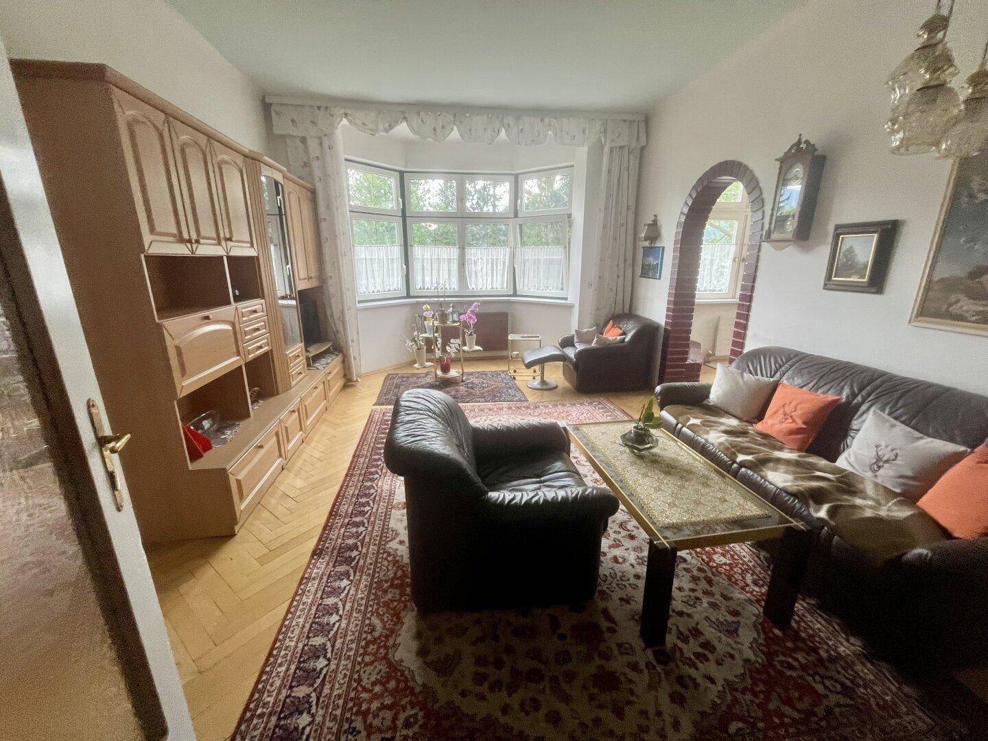 Geräumiges Wohnzimmer mit traditionellen Möbeln, Parkettboden und Erkerfenster.