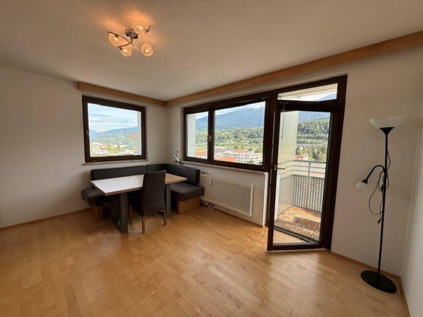 Heller Wohn-Essbereich mit Parkettboden, gemütlicher Eckbank und Zugang zum Balkon mit Bergblick.