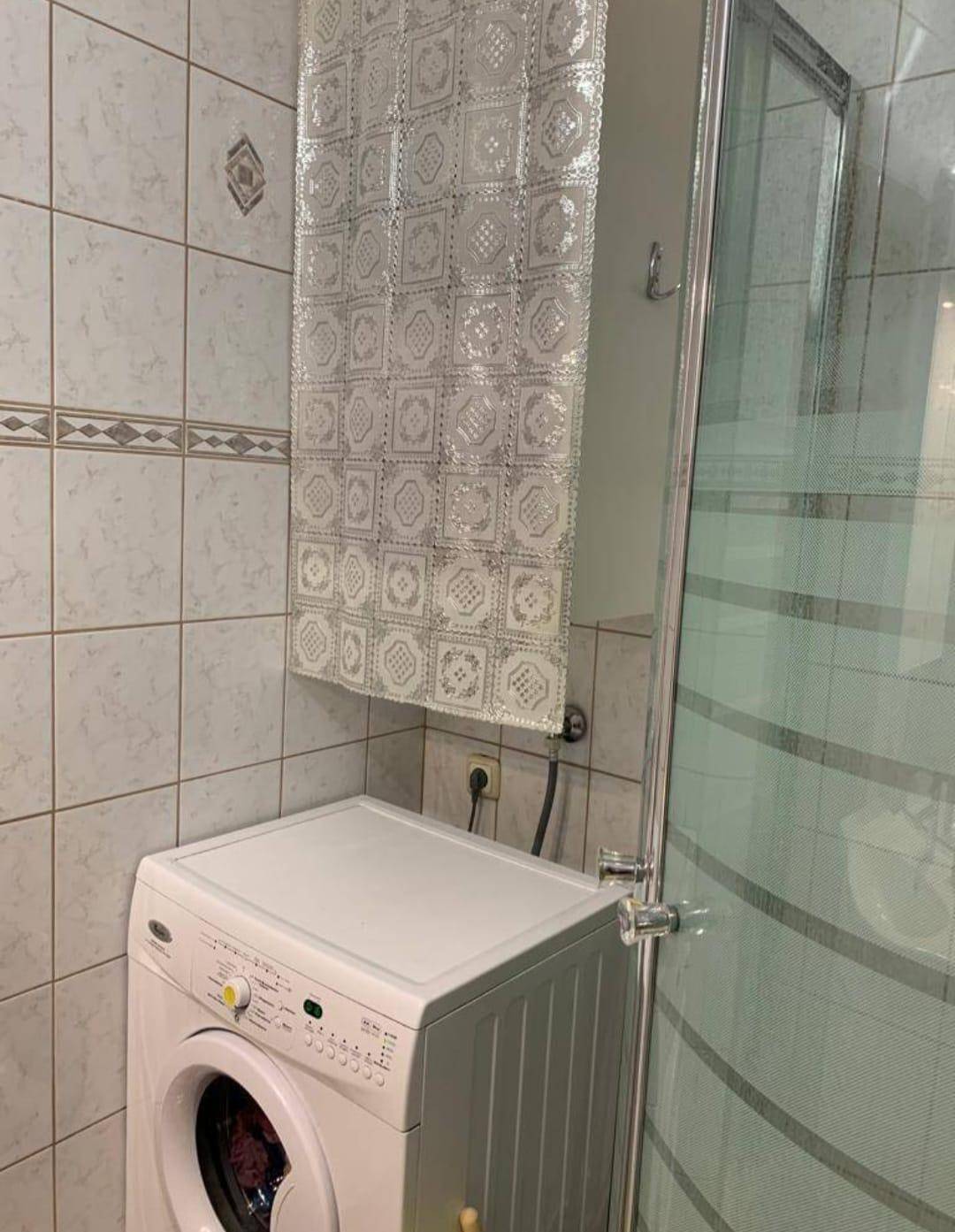 Badezimmer mit Duschkabine und Waschmaschine.
