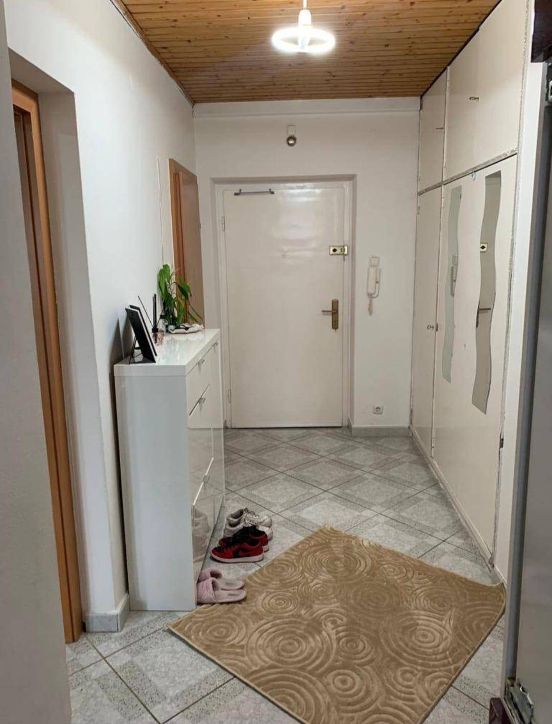 Eingangsbereich mit Fliesenboden, Einbauschränken und Holzdecke.