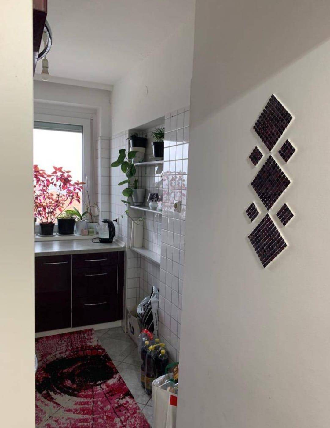 Küchenbereich mit weißen Wandfliesen, Fenster und dekorativen Elementen.