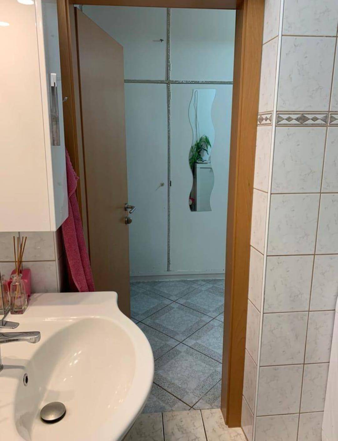 Badezimmer mit Waschbecken und Zugang zu einem angrenzenden Raum.