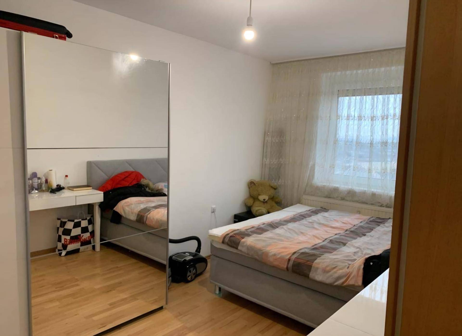 Schlafzimmer mit Doppelbett, Spiegelschrank und Schreibtisch.
