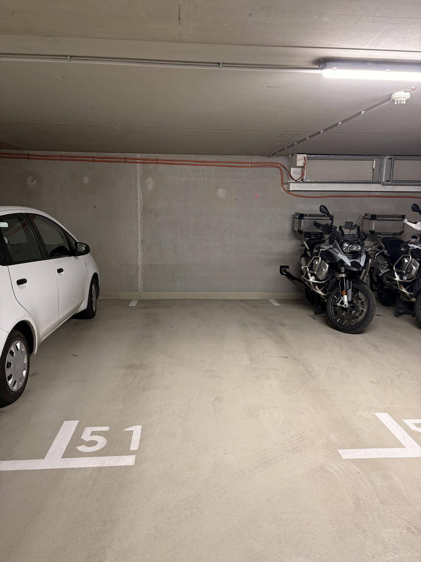 Parkplatz in der Tiefgarage mit markierter Stellfläche und Motorrädern.