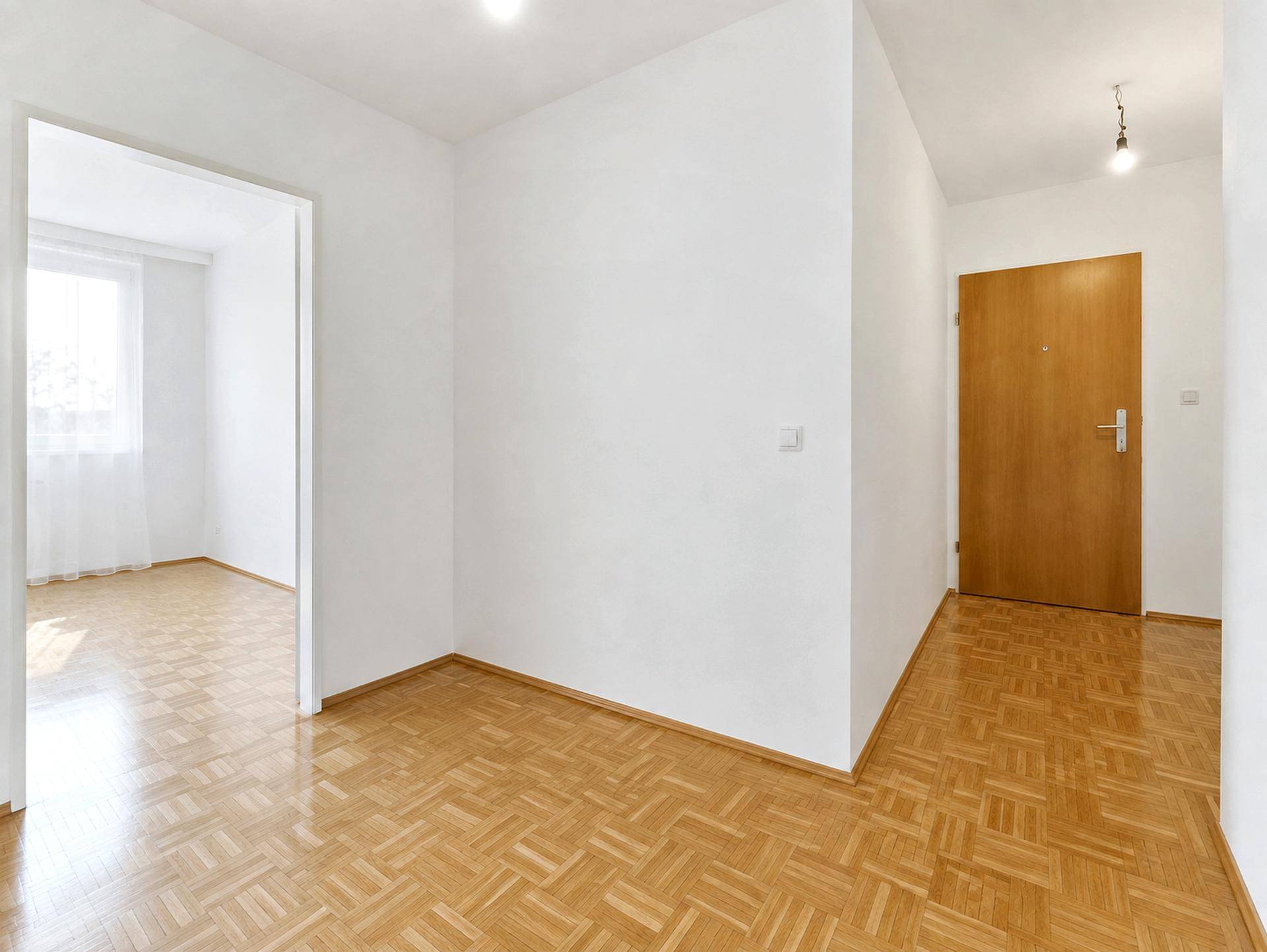 Heller Flur mit Parkettboden und Holztür, der zu weiteren Räumen der Wohnung führt.