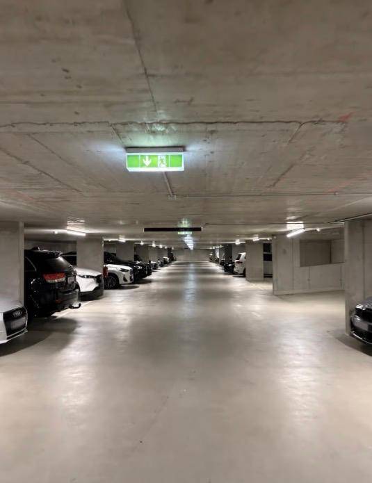 Lange Reihe von Parkplätzen in einer modernen und gut beleuchteten Tiefgarage mit vielen Fahrzeugen.