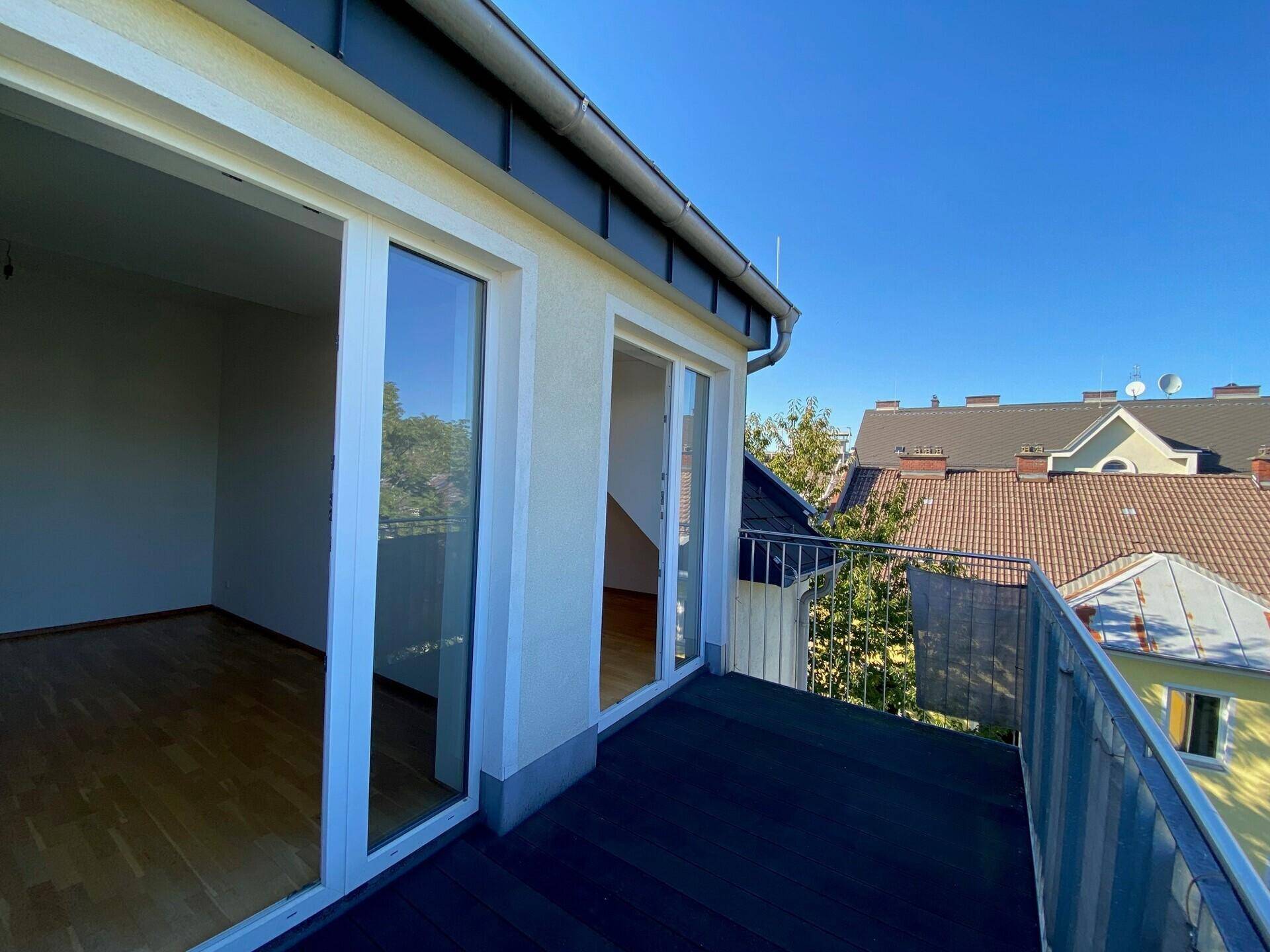 Geräumiger Balkon mit Zugang zu einem hellen Innenraum und Blick auf die Umgebung.