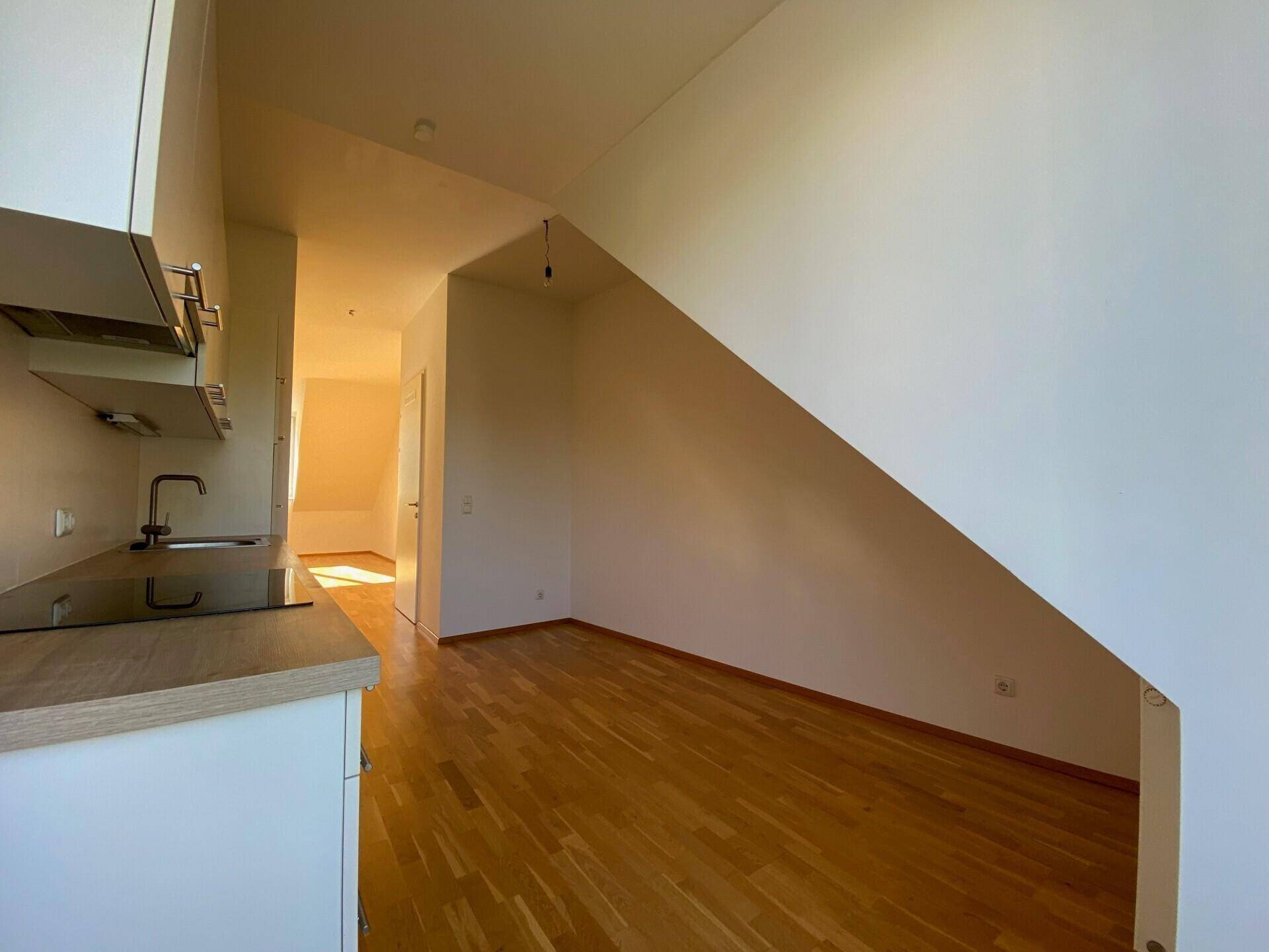 Funktionale Küchenzeile mit Holzboden und schräger Wand in einem hellen Wohnbereich.