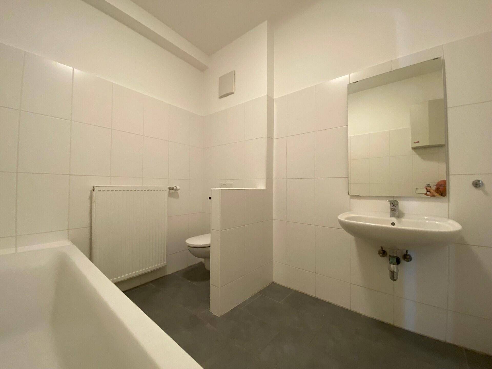 Funktionales Badezimmer mit Badewanne, WC, Waschbecken und weißen Fliesen.