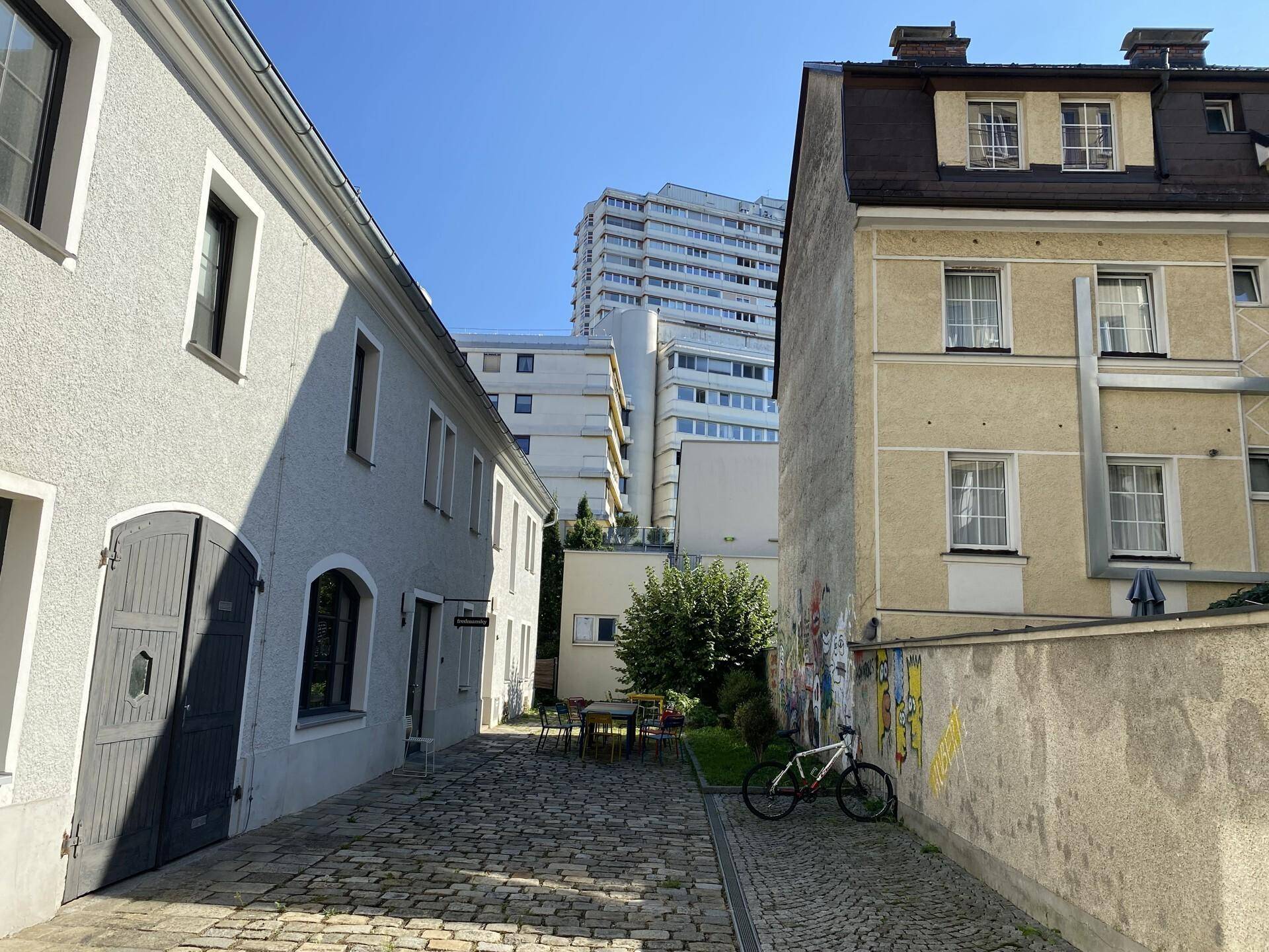 Historischer Innenhof mit Kopfsteinpflaster und Blick auf moderne und ältere Gebäude.