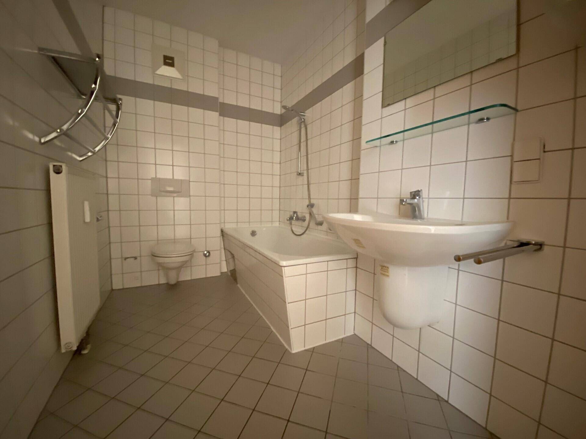 Gefliestes Badezimmer mit Badewanne, Dusche, WC und Waschbecken, in einem funktionalen Design gehalten.
