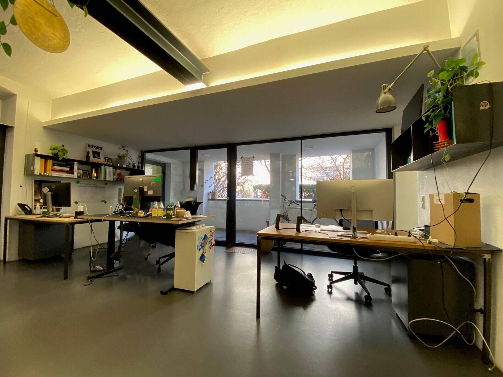 Geräumiges Büro mit mehreren Schreibtischen, großen Fenstern und einem angenehmen Blick ins Grüne.