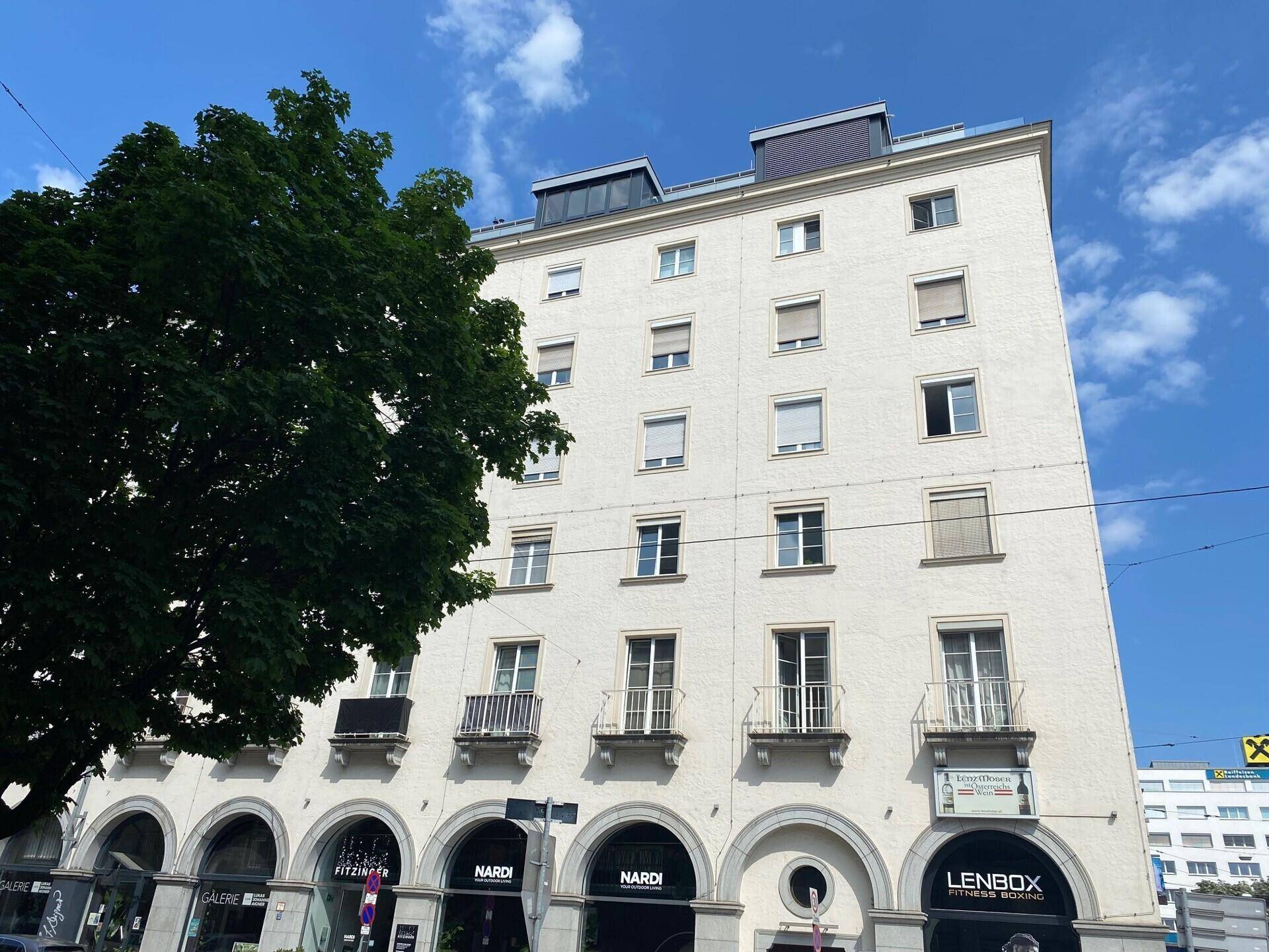 Mehrstöckiges Gebäude mit weißer Fassade, vielen Fenstern und kleinen Balkonen.