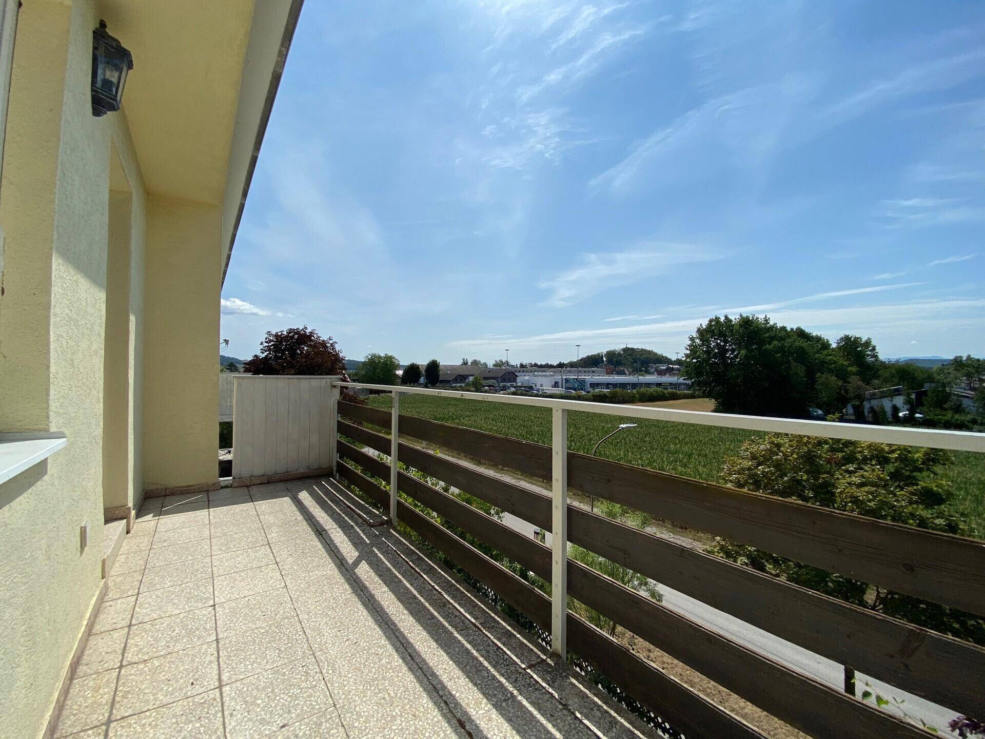 Balkon mit Fliesenboden und weitem Blick über die Umgebung und angrenzende Felder.