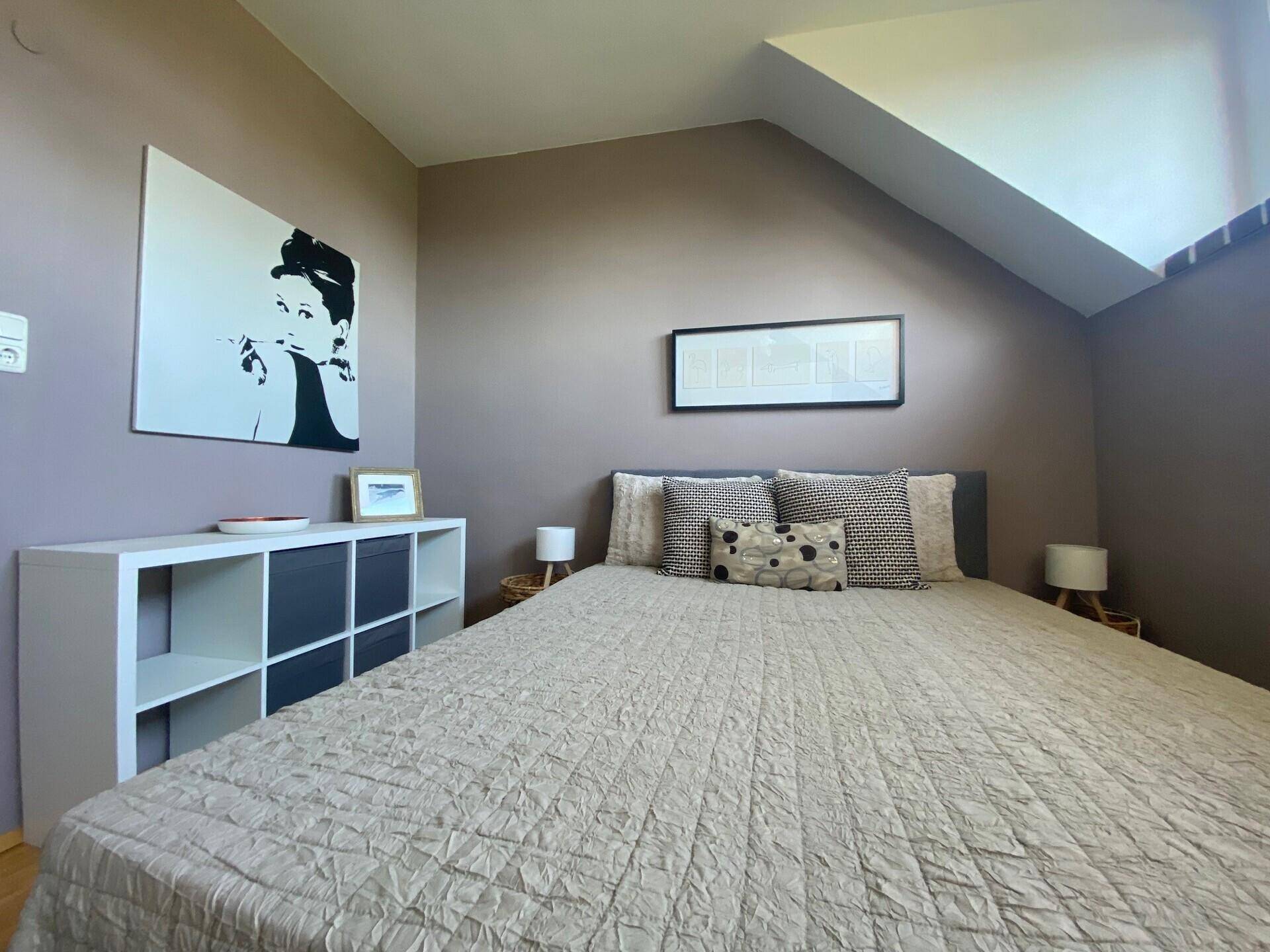 Gemütliches Schlafzimmer mit Doppelbett, Holzboden und moderner Wanddekoration.