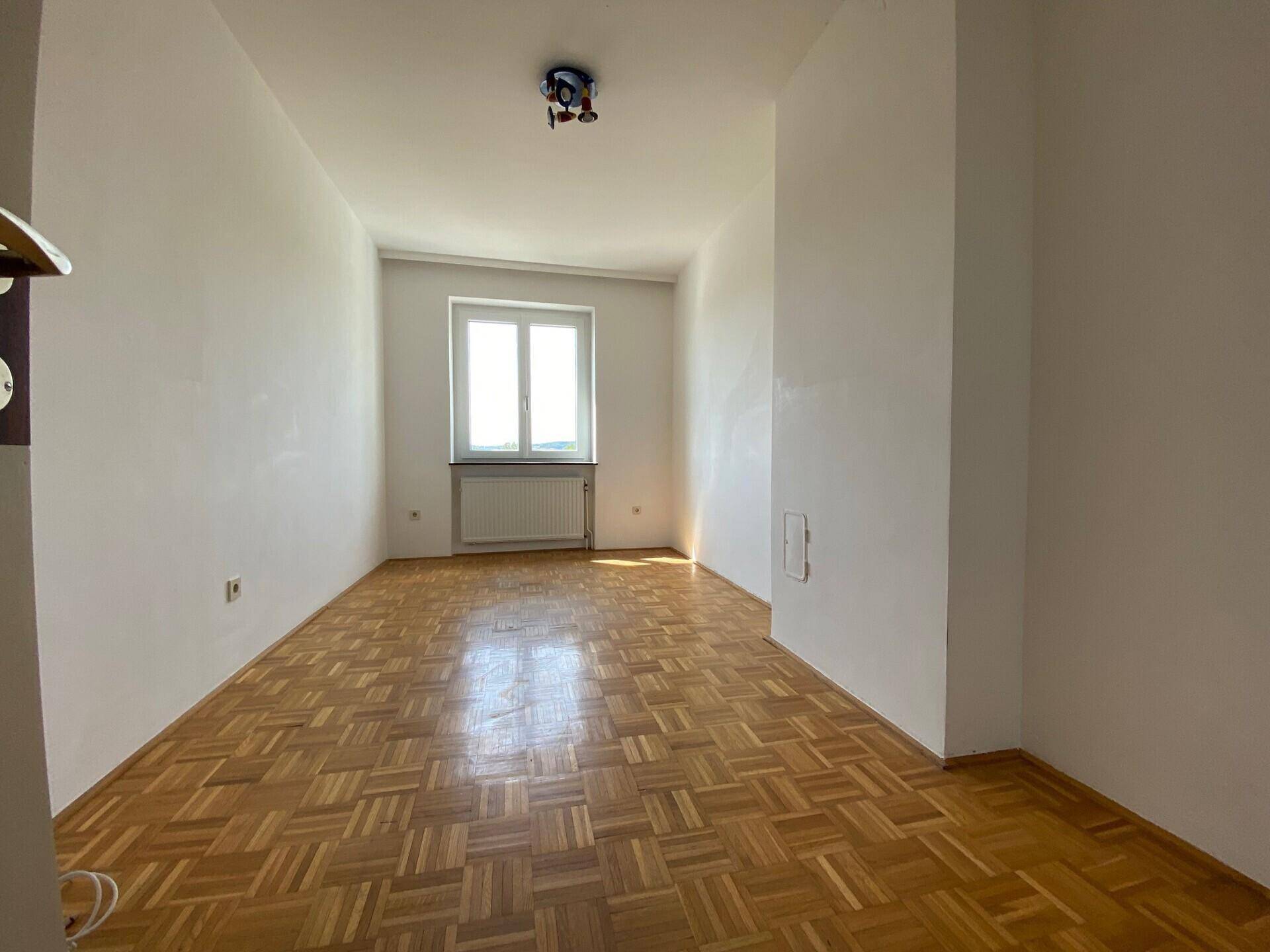 Gemütliches Zimmer mit Parkettboden und einem Fenster, das viel Helligkeit spendet.