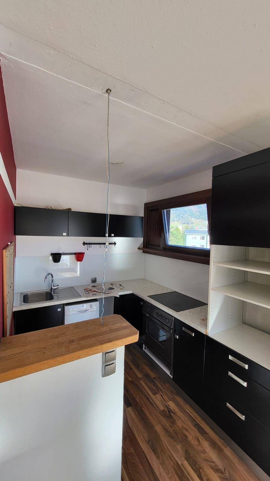 Moderne Küche mit schwarzen Schränken, weißer Arbeitsplatte und integrierter Spülmaschine.