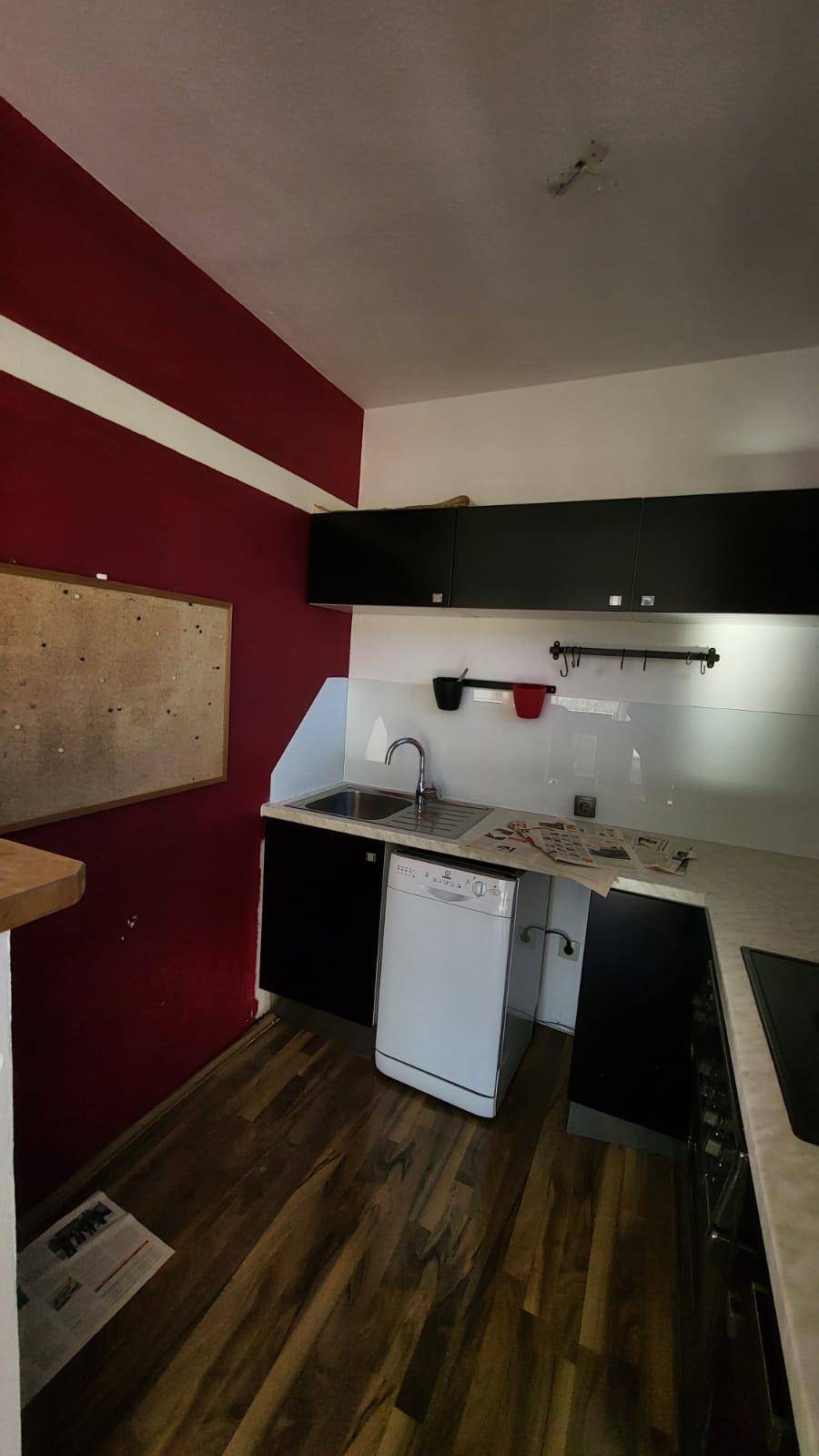 Funktionale Küche mit roten Akzentwänden, Spülbecken und integrierter Spülmaschine.