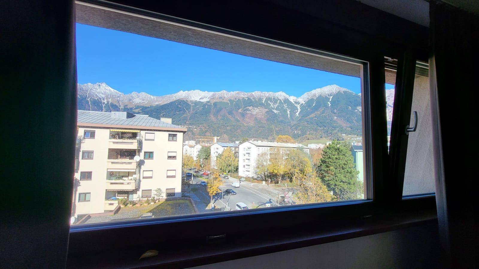 Weitblick aus dem Fenster auf die Stadt und die majestätische Bergkette.