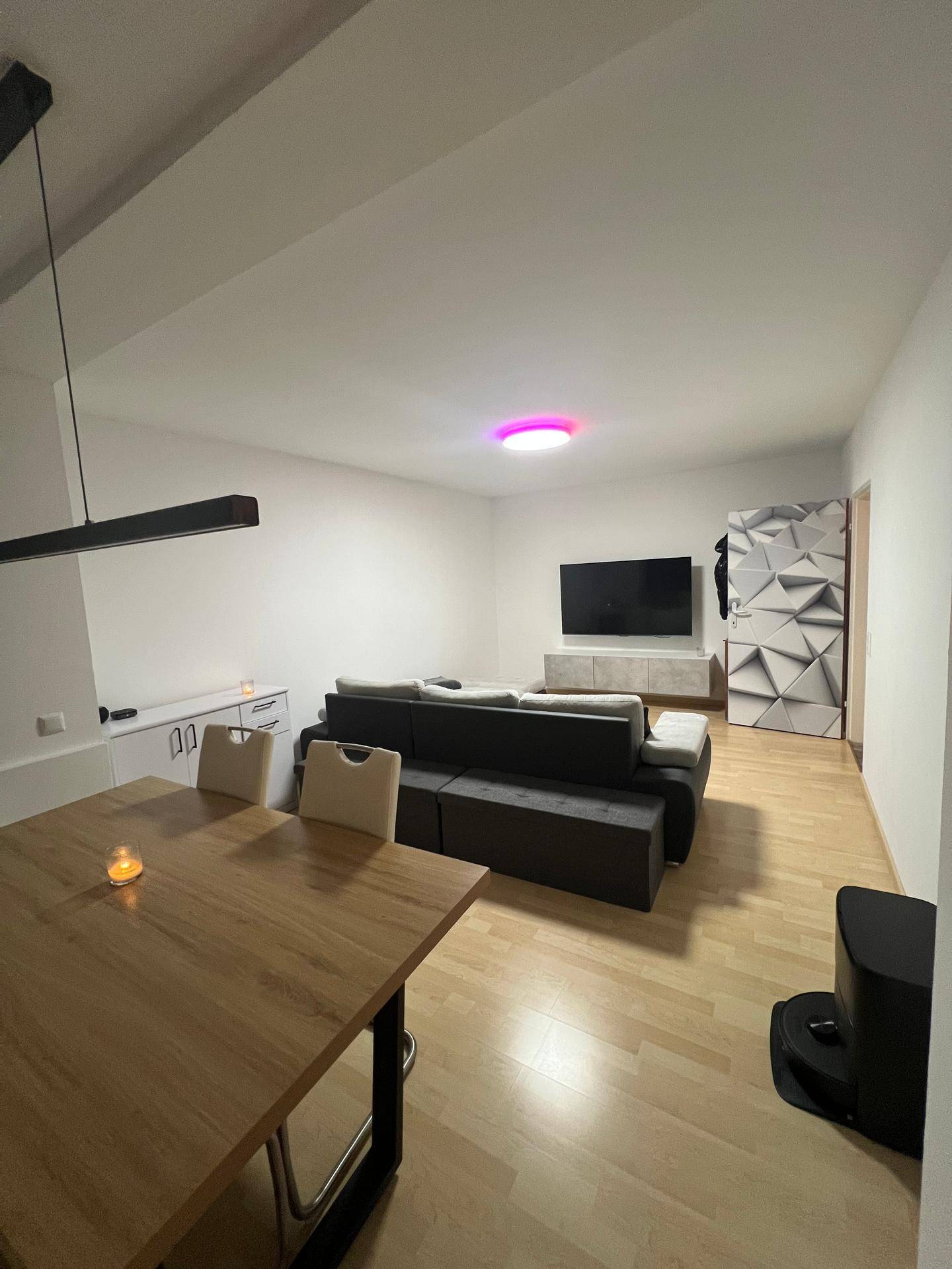 Gemütlicher Wohnbereich mit Fernseher, moderner Eckcouch und dekorativer Wandgestaltung.