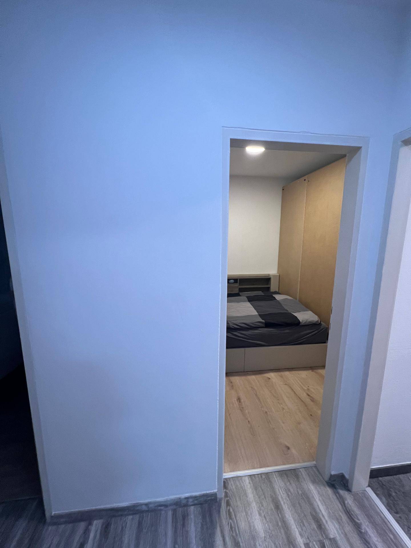 Blick in ein Schlafzimmer mit modernem Bett und hellem Laminatboden.