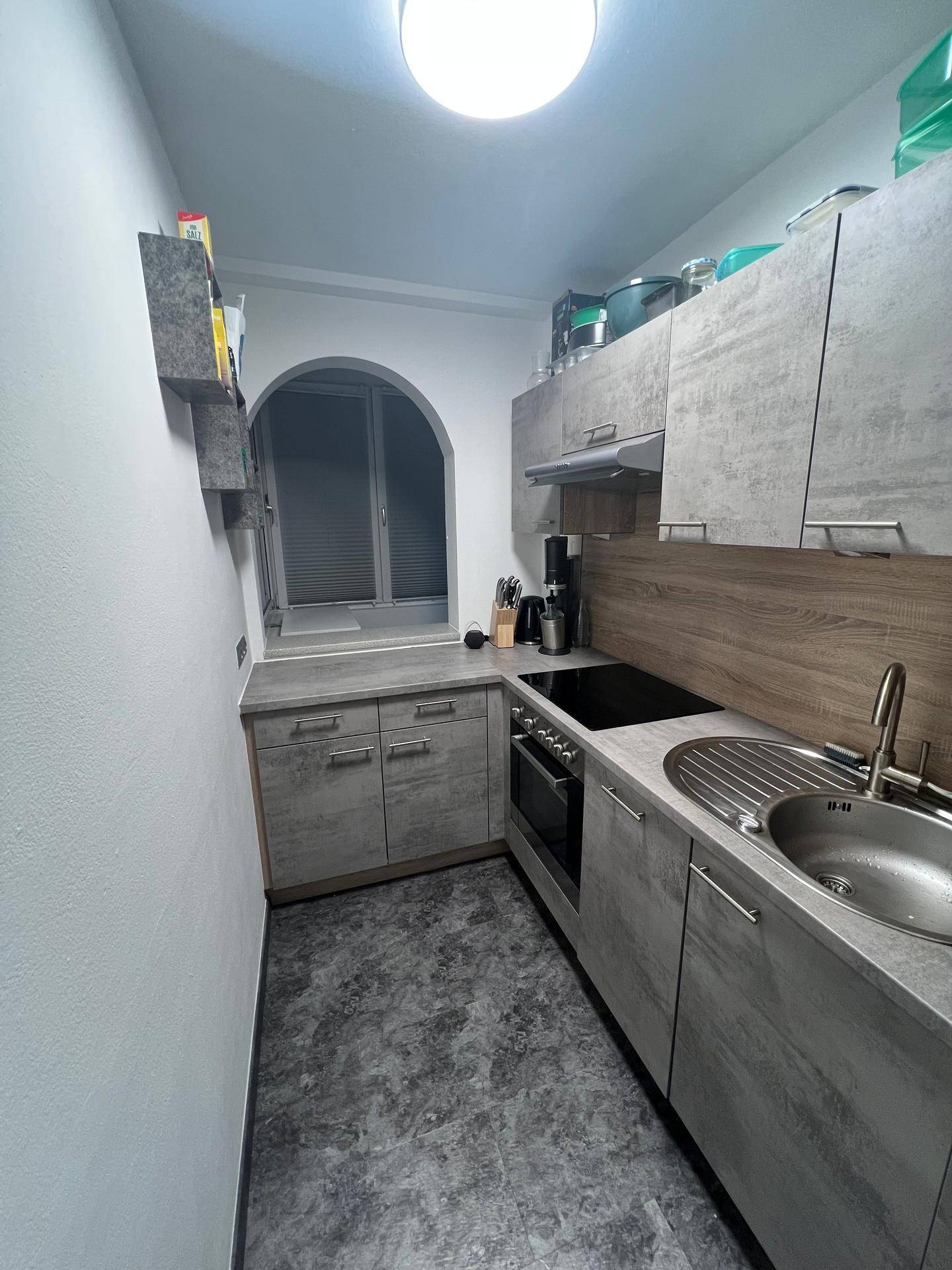 Funktionale Küche mit Spüle, Kochfeld und Backofen in modernem Grau-Design.