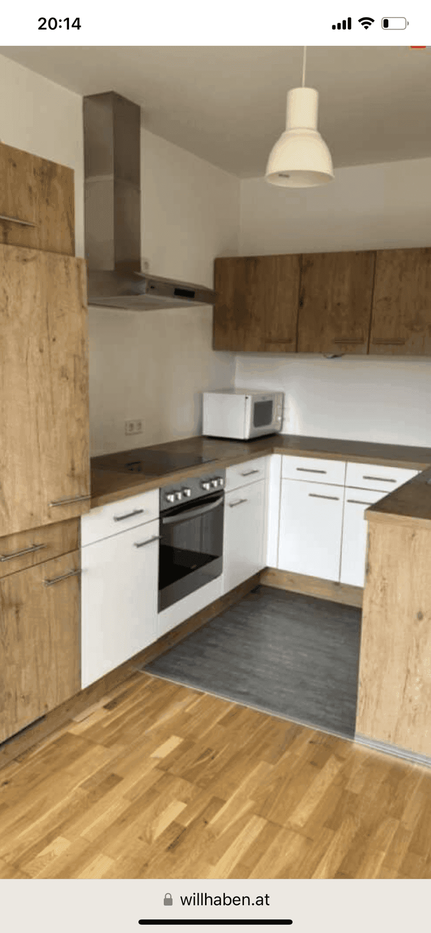 Funktionale Küche mit Holz- und weißen Fronten, ausgestattet mit Herd, Backofen und Dunstabzugshaube.